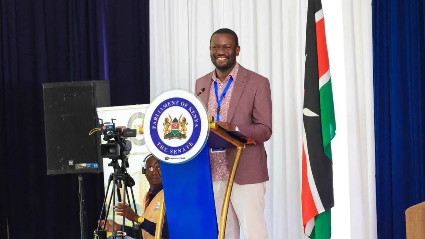 Sen. Edwin Sifuna smiling at a Parliament of Kenya Senate podium.
